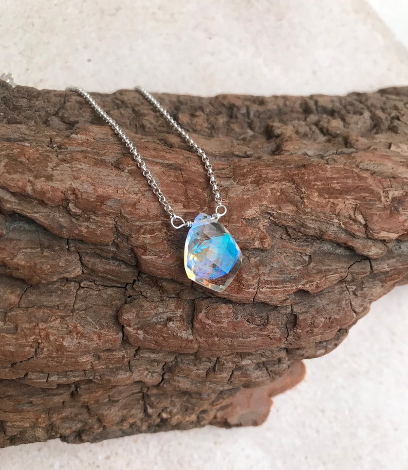 May include: A silver chain necklace with a iridescent, faceted gemstone pendant.
