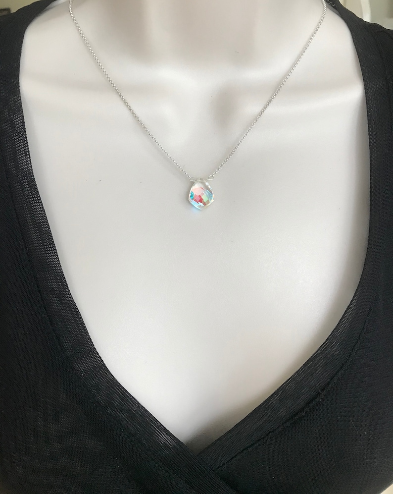 May include: A silver chain necklace with a small, iridescent, faceted gemstone pendant.