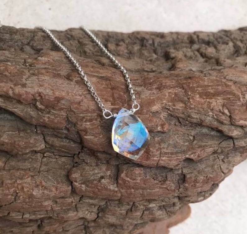 May include: A silver chain necklace with a teardrop-shaped iridescent gemstone pendant.