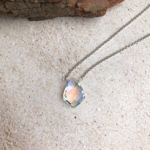 May include: A silver chain necklace with a clear iridescent crystal pendant.