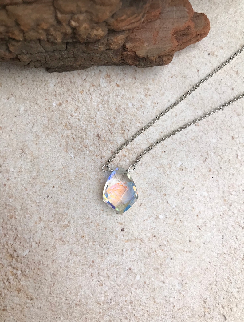 May include: A silver chain necklace with a clear iridescent crystal pendant.