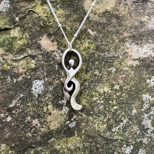 Pu&ograve; includere: Una collana d'argento con un ciondolo che rappresenta una figura umana stilizzata. Il ciondolo &egrave; un design semplice e astratto con una testa circolare e un corpo fluido.