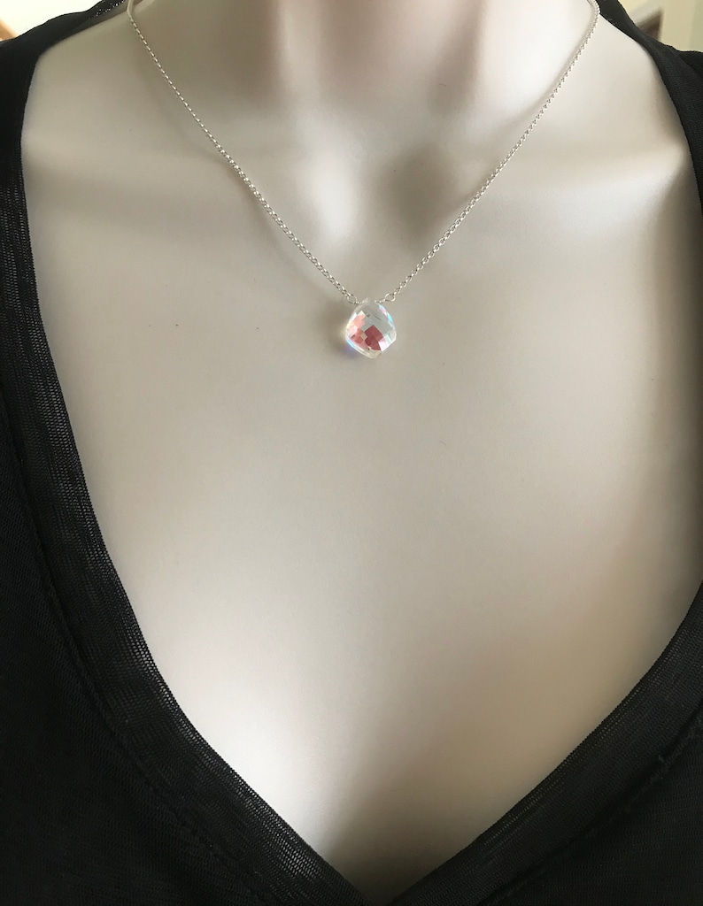 May include: A silver chain necklace with a clear iridescent teardrop-shaped pendant.