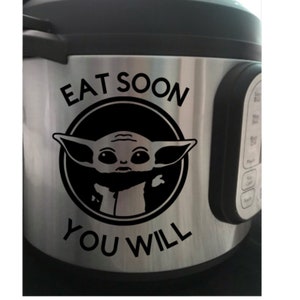 Può includere: Una pentola a pressione Instant Pot in acciaio inossidabile con un adesivo in vinile nero che presenta un personaggio dei cartoni animati della saga di Star Wars, noto come "Baby Yoda", con il testo "Eat Soon You Will".