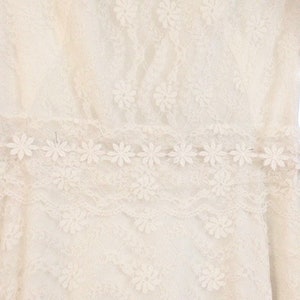 May include: White lace fabric with a delicate floral pattern. The lace has a scalloped edge and is perfect for a variety of crafting projects.