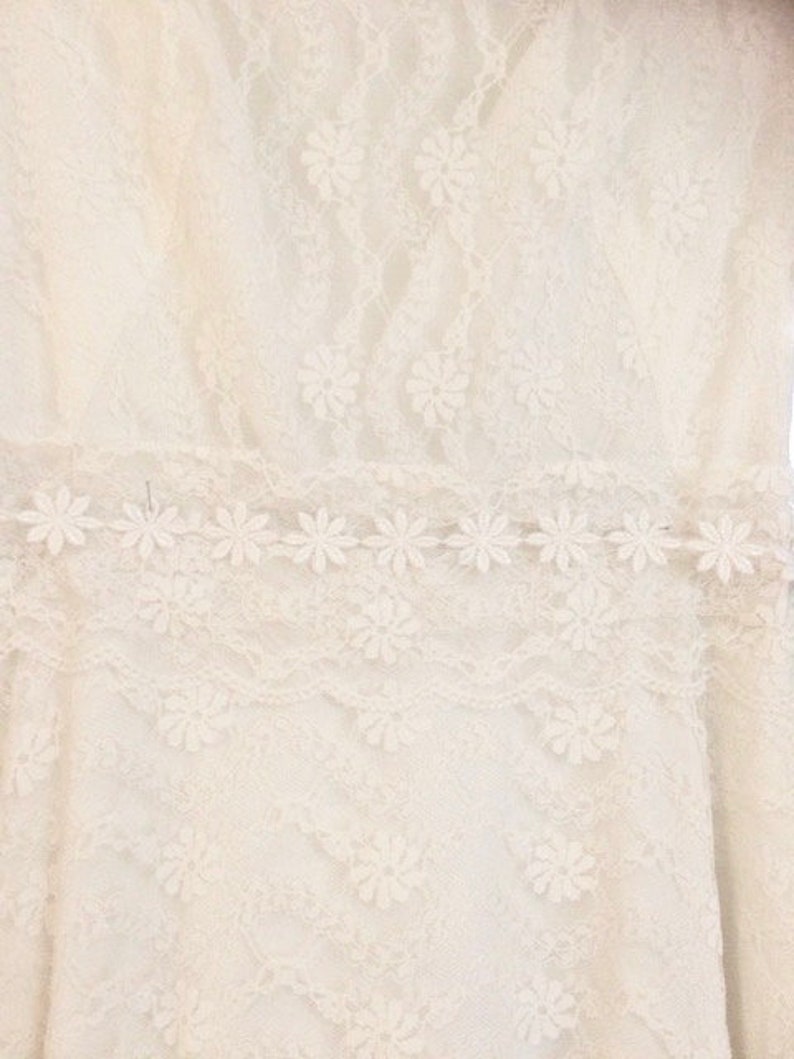 May include: White lace fabric with a delicate floral pattern. The lace has a scalloped edge and is perfect for a variety of crafting projects.