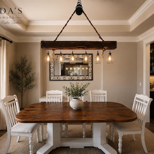 May include: A rectangular wooden beam chandelier suspended by a rope and pulley system, featuring six hanging glass pendant lights with Edison-style bulbs. The fixture is made of dark, weathered timber and hangs above a wooden dining table.