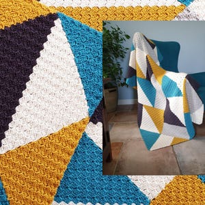 May include: A crocheted throw blanket with a geometric pattern in shades of teal, mustard yellow, white, and gray. The blanket is draped over a chair.