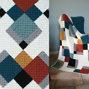 May include: A crocheted blanket with a geometric pattern in shades of white, grey, teal, mustard yellow, and rust. The blanket is folded and draped over a teal armchair.