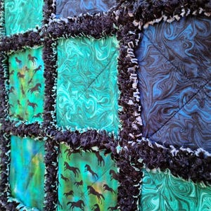 Close-up perspective of the quilted squares, emphasizing the texture of the dark frayed rag edges between panels.