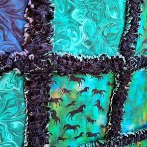Detailed macro view showing the dark frayed seams separating quilted squares of teal marble and horse-print fabrics.