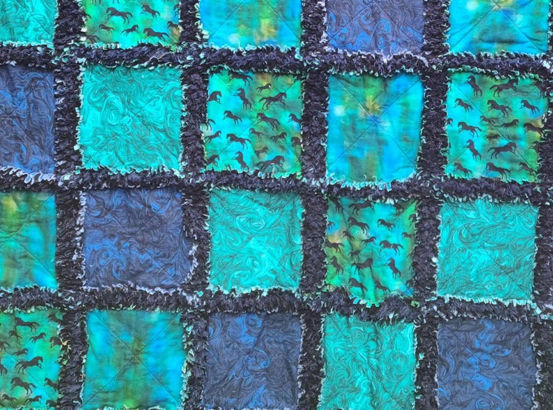 Close-up horizontal section of the quilt showcasing multiple textured blocks in shades of blue and teal green.