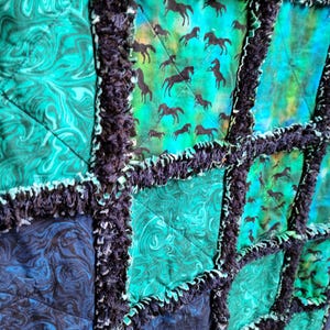 Close-up view of several patchwork squares displaying swirling blue patterns and black galloping horse silhouettes.