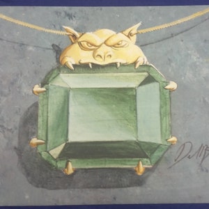 May include: A green gemstone pendant with a gold setting. A small, gold, cartoon-like creature with a menacing expression is biting the pendant.