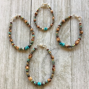 Puede incluir: Tres pulseras de cuentas con cuentas turquesas y marrones. Las pulseras est&aacute;n sobre un fondo de madera blanco.