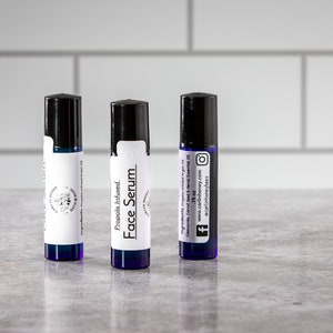 May include: Three small blue glass bottles with black roll-on tops. Each bottle has a white label with black text that reads "Propolis Infused Face Serum". The label on the right bottle also includes the text "Ingredients: Propolis Infused, Chamomile, Carrot Seed &  Merlot Essential Oil. .75 oz. www.carlinhoney.com @carlinhoneybees".