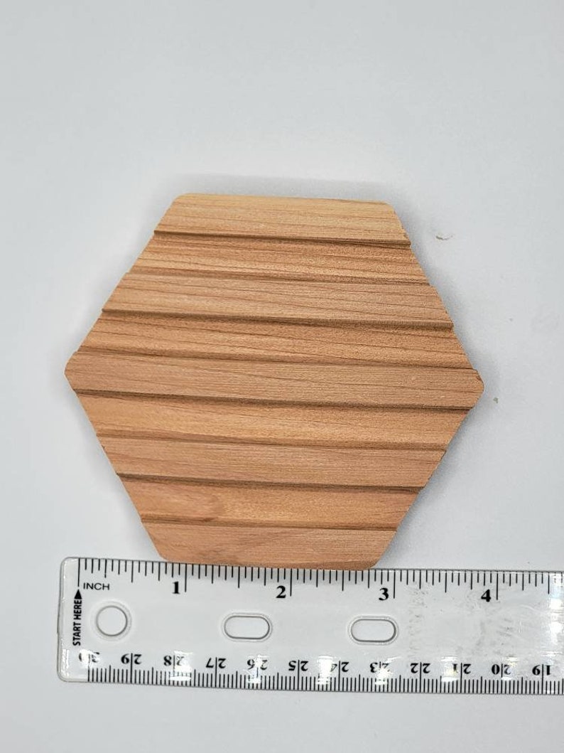 May include: A hexagonal wooden soap dish with grooves on the surface. The dish is approximately 3 inches wide.