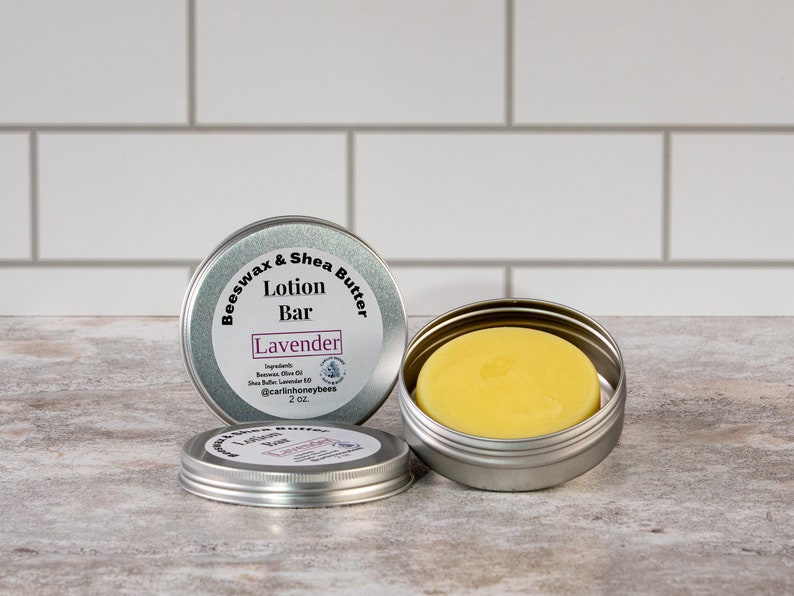 May include: A silver tin with a label that reads "Beeswax & Shea Butter Lotion Bar Lavender" and contains a yellow lotion bar. The tin is 2 oz.