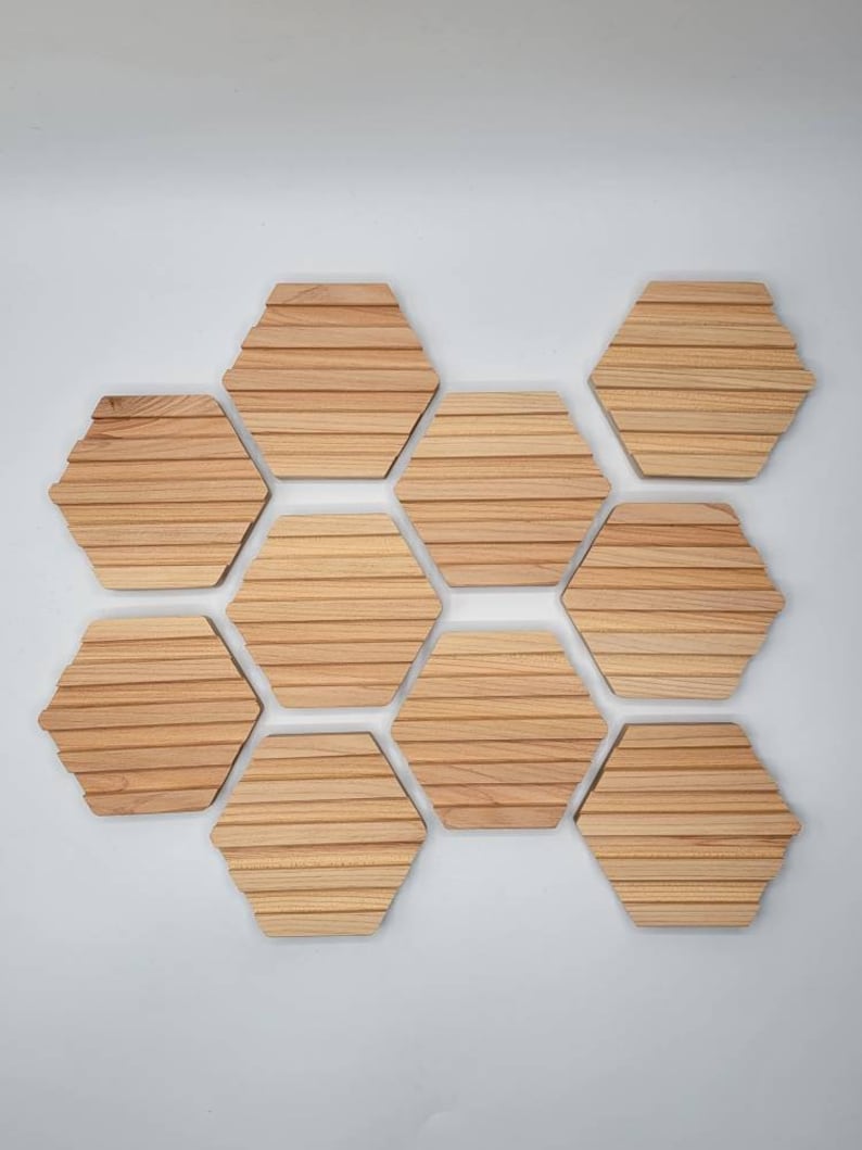 May include: Nine wooden hexagonal coasters arranged in a honeycomb pattern. The coasters are made of light brown wood with a grooved texture.