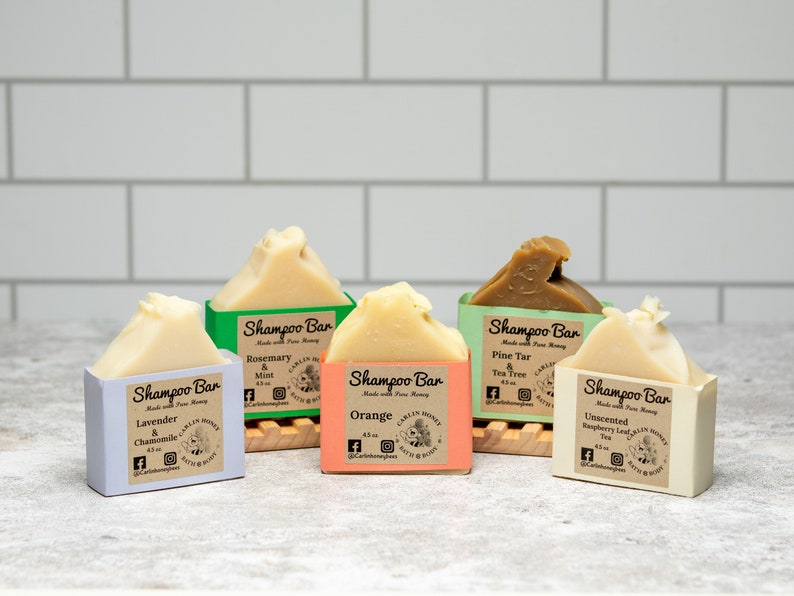 May include: Five rectangular shampoo bars with labels reading Shampoo Bar Made with Pure Honey. Scents include Lavender & Chamomile, Rosemary & Mint, Orange, Pine Tar & Tea Tree, and Unscented Raspberry Leaf Tea. Each bar weighs 4.5 oz.