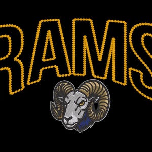 Pode incluir: Um design bordado sobre fundo preto com a palavra RAMS em letras amarelas grossas que lembram uma corda. Abaixo do texto, há uma ilustração detalhada de uma cabeça de carneiro com chifres curvos, em tons de cinza, branco e azul.