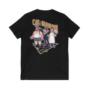 May include: Black v-neck t-shirt with a graphic of three cartoon men playing shuffleboard. The text "OLD GUYS RULE" is above the figures. The design includes a shuffleboard court and gold pucks.