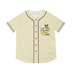 Puede incluir: Camiseta de béisbol color crema con ribetes y botones negros. La camiseta muestra el texto "Allentown Peanuts Baseball Club" con un personaje de cacahuete de dibujos animados y el año "Est. 1898" en amarillo y negro.