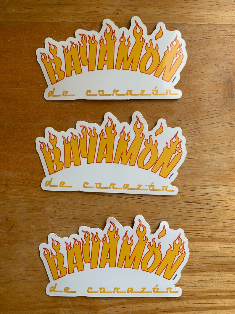 Może przedstawiać: Trzy białe naklejki z wzorem ż&oacute;łtych i czerwonych płomieni. Na każdej naklejce nadrukowany jest tekst "BAYAMON de coraz&oacute;n".