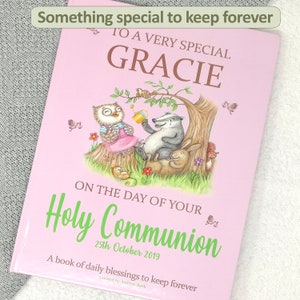 Op de afbeelding: Een roze boek met de titel "Something special to keep forever" en "To a very special Gracie". Het boek heeft een illustratie van een uil, een das en een konijn in een bosrijke omgeving. De tekst "On the day of your Holy Communion 25th October 2019" staat op het boek gedrukt. Het boek heeft ook de tekst "A book of daily blessings to keep forever" onderaan gedrukt.