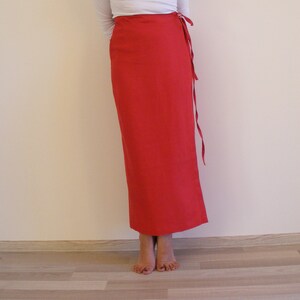 May include: A long, red wrap skirt with a tie at the waist. The skirt is made of a soft, flowing fabric.