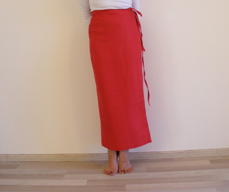 May include: A long, red wrap skirt with a tie at the waist. The skirt is made of a soft, flowing fabric.