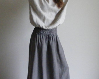May include: A light gray linen blouse with long sleeves and a round neckline paired with a gray elastic waist maxi skirt. The outfit is made of a soft, flowing fabric, perfect for a casual, comfortable look.
