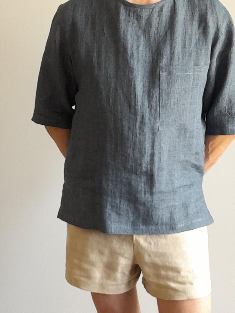 K&ouml;nnte beinhalten: Ein dunkelblaues Leinenhemd mit einer Brusttasche und kurzen &Auml;rmeln, kombiniert mit einer beigefarbenen Leinenhose.