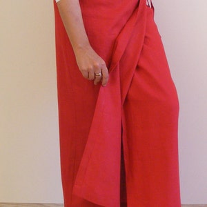 May include: A red wrap skirt with a long, flowing design. The skirt is tied at the waist with a thin fabric belt.