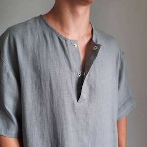 Op de afbeelding: Een grijs linnen shirt met korte mouwen en een knoopsluiting.