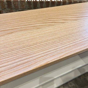 Puede incluir: Una mesa con una tapa de madera de roble natural y estantes blancos. La mesa tiene un patr&oacute;n de veta de madera clara.