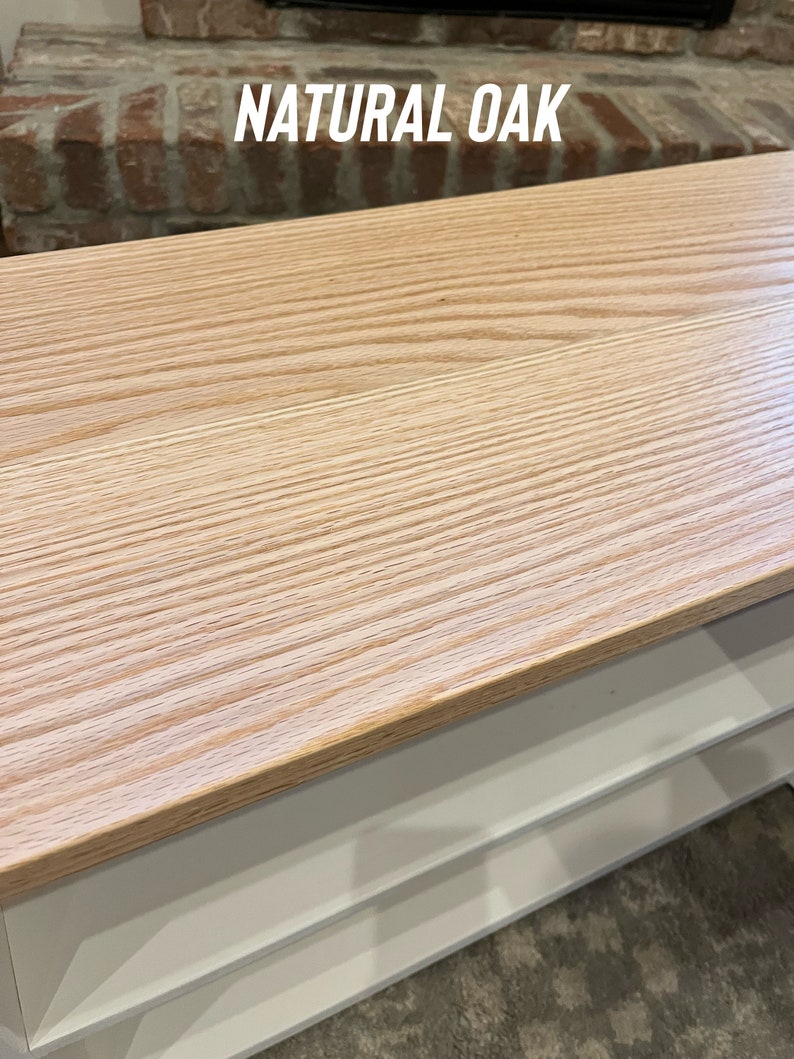 Puede incluir: Una mesa con una tapa de madera de roble natural y estantes blancos. La mesa tiene un patr&oacute;n de veta de madera clara.