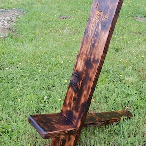 May include: A dark brown wooden chair with a carved design on the back. The chair is made of rough-hewn wood and has a rustic look.