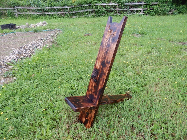 May include: A rustic wooden chair with a carved design on the back. The chair is dark brown and has a simple, minimalist design.