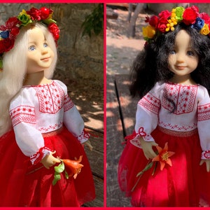 Op de afbeelding: Twee poppen in traditionele Oekraïense outfits. Elke pop heeft een bloemenkrans en houdt een bloem vast. De poppen dragen witte blouses met rode borduursels, rode rokken en gouden randen. Eén pop heeft blond haar en de andere heeft zwart haar.