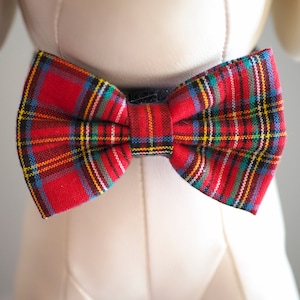 May include: Red and black plaid bow tie with a black strap.