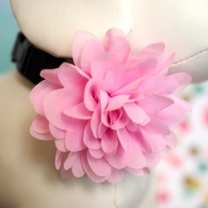 May include: A pink fabric flower with multiple layers of petals.