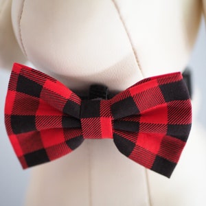 May include: A red and black plaid bow tie. The bow tie is tied around the neck of a white stuffed animal.