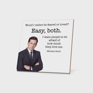May include: A white square decorative item with the quote "Would I rather be feared or loved? Easy, both. I want people to be afraid of how much they love me. - Michael Scott" and a photo of a man in a suit.