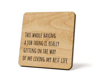 Peut inclure: Sous-verre en bois avec le texte "THIS WHOLE HAVING A JOB THING IS REALLY GETTING IN THE WAY OF ME LIVING MY BEST LIFE" en lettres noires.