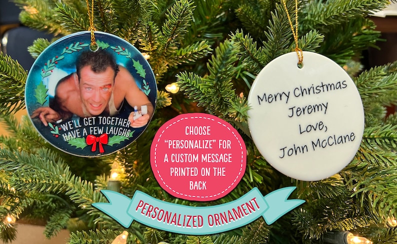 Op de afbeelding: Twee ronde witte kerstballen van keramiek. E&eacute;n kerstbal heeft een foto van Bruce Willis uit de film Die Hard met de tekst "We'll get together have a few laughs". De andere kerstbal heeft de tekst "Merry Christmas Jeremy Love, John McClane".