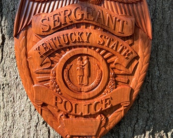 May include: A wooden police badge with the words "Sergeant Kentucky State Police" and an eagle design.