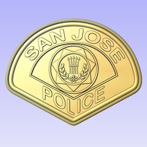 Puede incluir: Una placa de policía de San José de color dorado con una estrella de cinco puntas y una corona de laurel que rodea una puerta estilizada con tres lanzas.