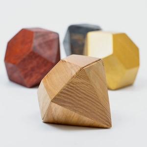 Pode incluir: Quatro caixas geométricas de madeira em forma de diamantes. As caixas são pintadas em diferentes cores: vermelho, preto, dourado e madeira natural.