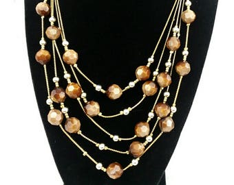 May include: A multi-strand necklace with brown faceted beads and gold chains.